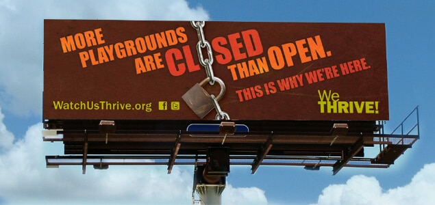 A highway advertising billboard that says "more playgrounds are closed than open. This is why we're here. We Thrive!"